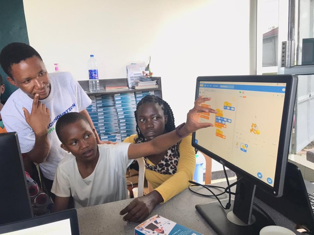 A Technovation mentor guiding girls as they code on a computer